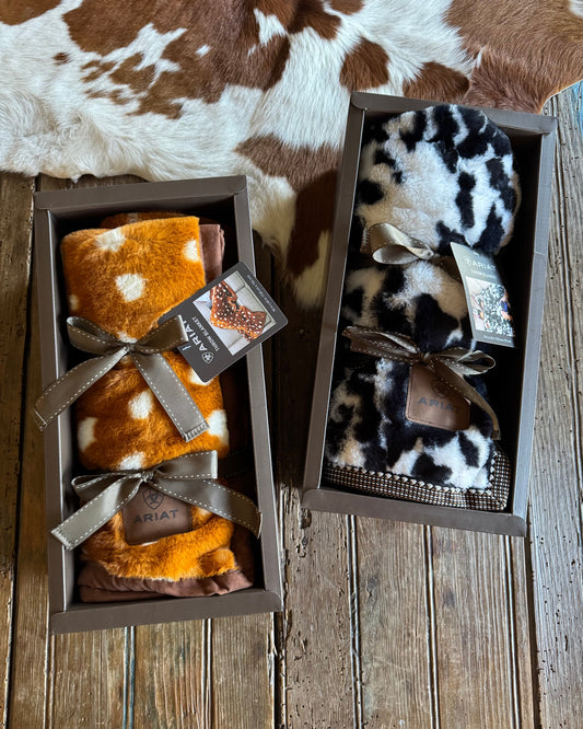 Two cowhide patterned blankets in wooden boxes on a wooden surface.