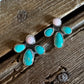 A pair of silver stud earrings with turquoise and pink stones, displayed on a rustic wooden surface.