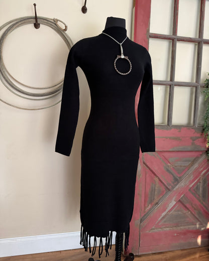 Black dress with fringe on a mannequin against a rustic background