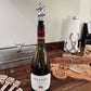 Wine bottle with a decorative stopper on a wooden surface, with MEIOMI branding.