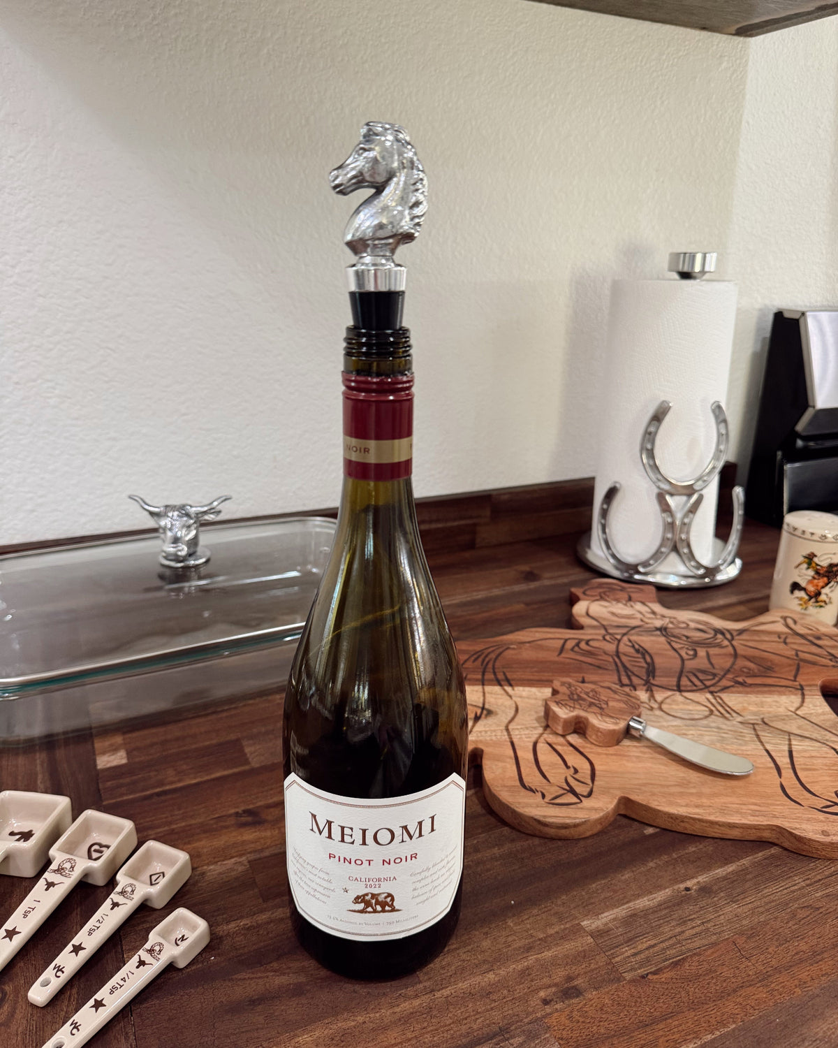Wine bottle with a decorative stopper on a wooden surface, with MEIOMI branding.