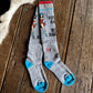 Gray socks with blue accents and graphic design on a wooden surface with cowhide rug