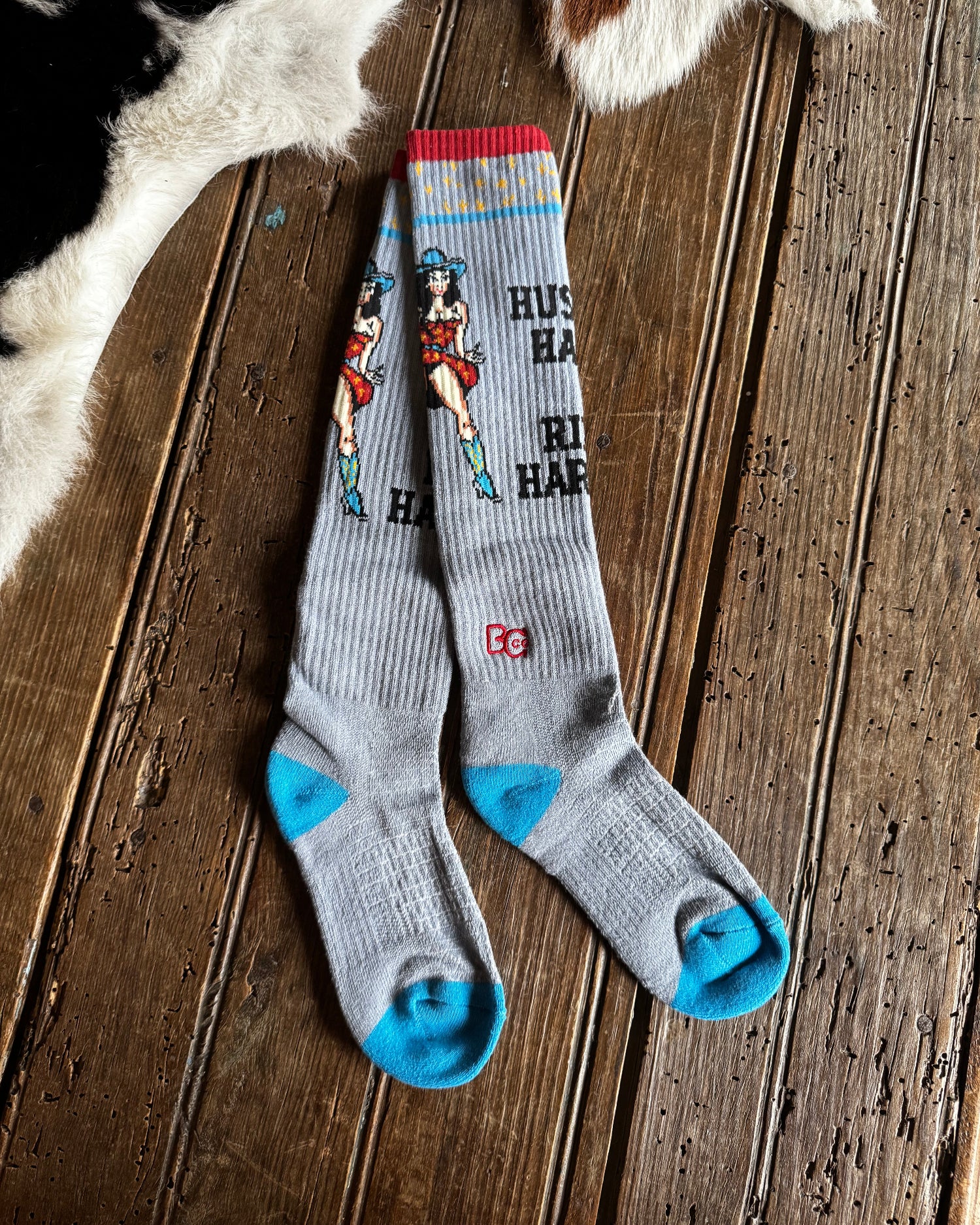 Gray socks with blue accents and graphic design on a wooden surface with cowhide rug