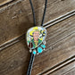 Bolo tie with a colorful pendant featuring a cowboy on a wooden surface