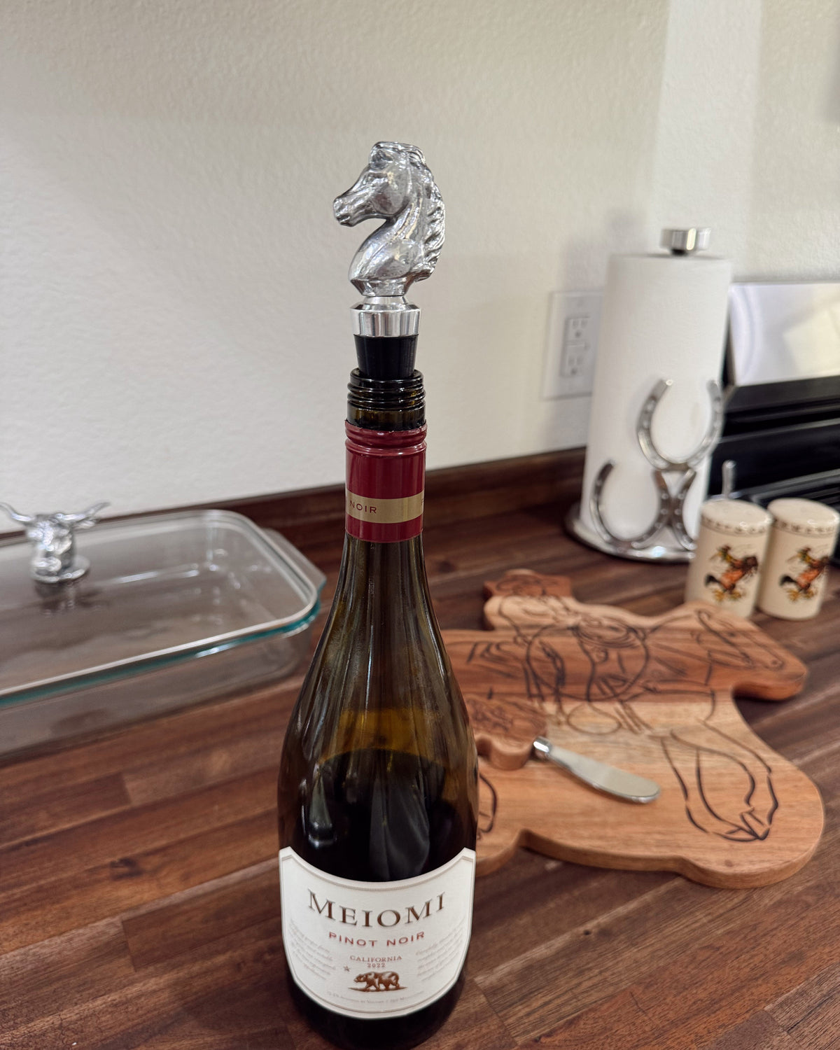 Wine bottle with a horse-shaped stopper on a wooden surface