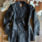 Dark jacket on a wooden surface with a cowhide rug in the background