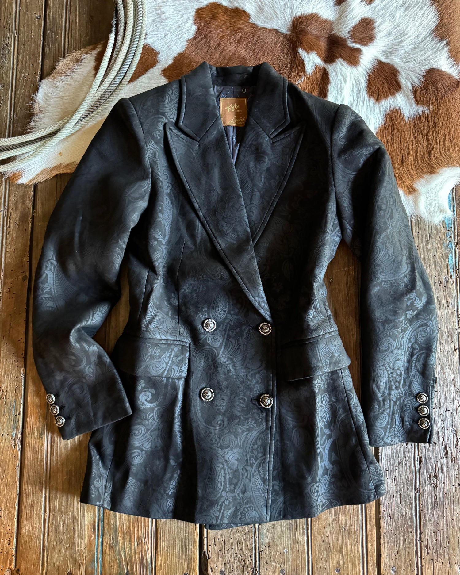 Dark jacket on a wooden surface with a cowhide rug in the background