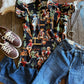 Blake Shirt (Cowgirl Pinup in Black) with jeans, shoes, and necklace on rustic wood background 