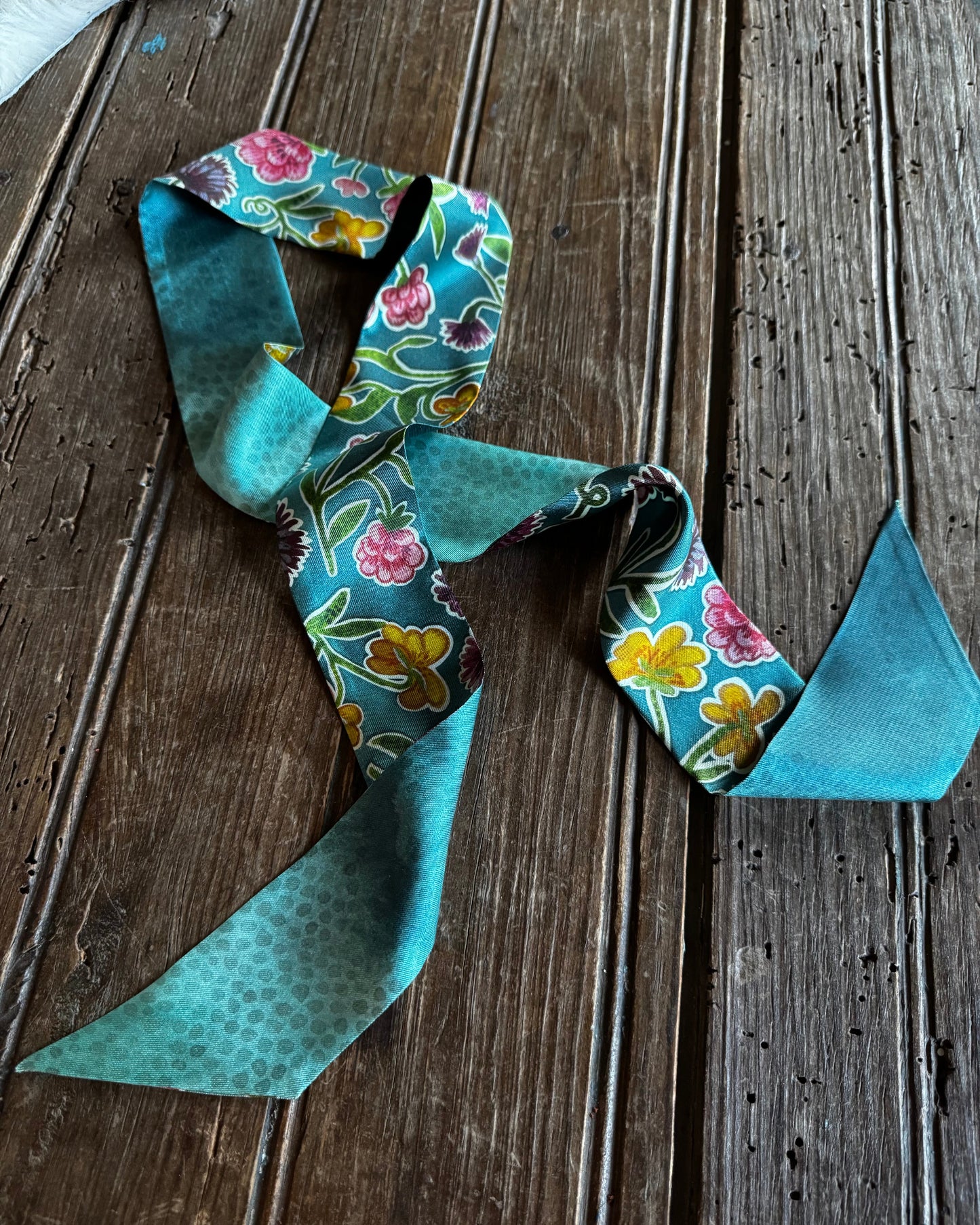 Twilly Scarf with flowers on a wooden surface