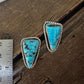 Turquoise earrings on a wooden surface with a ruler for scale.