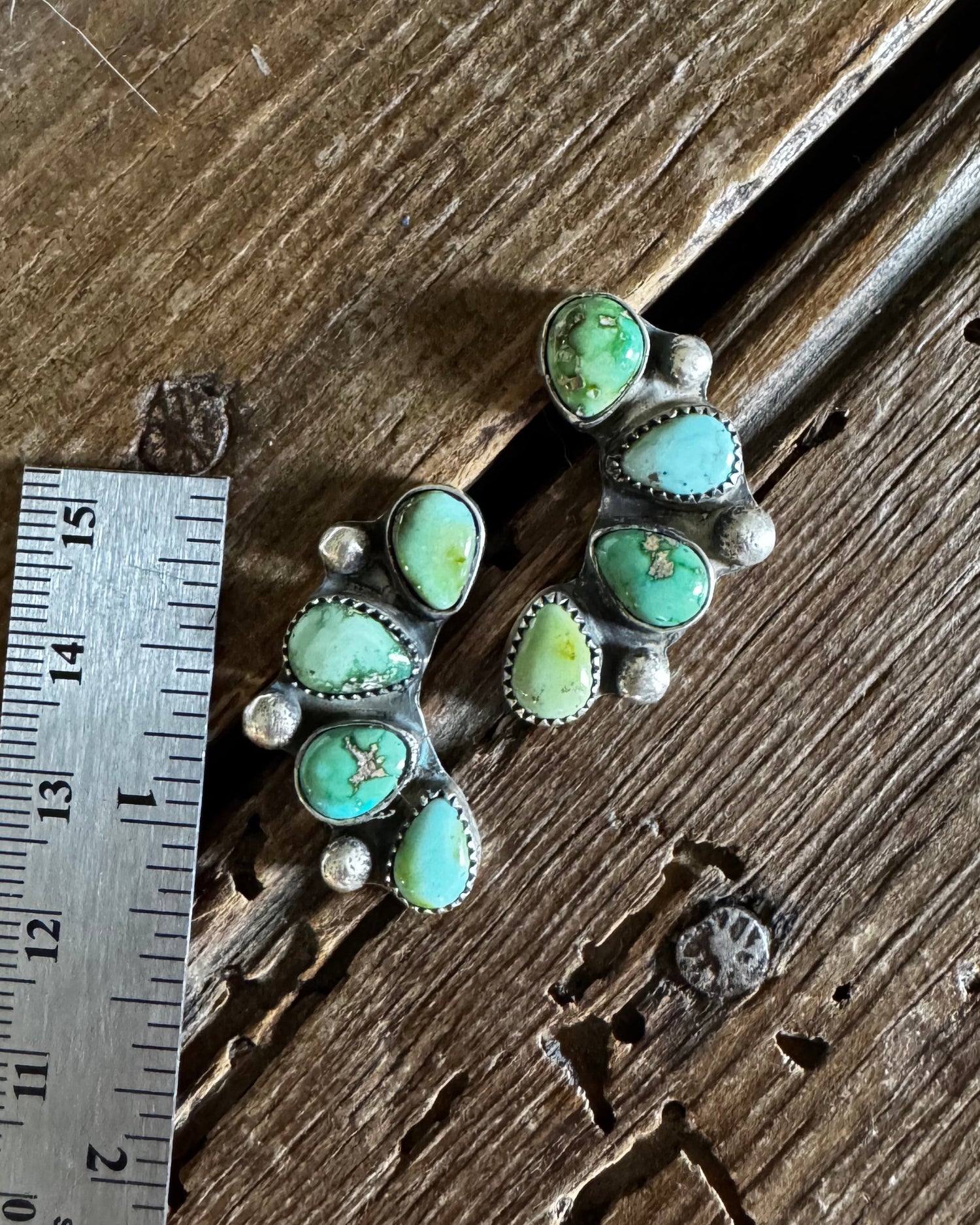 Turquoise stone jewelry piece on a wooden surface with a ruler for scale.