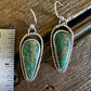 Pair of turquoise earrings on a wooden surface with a ruler for scale.