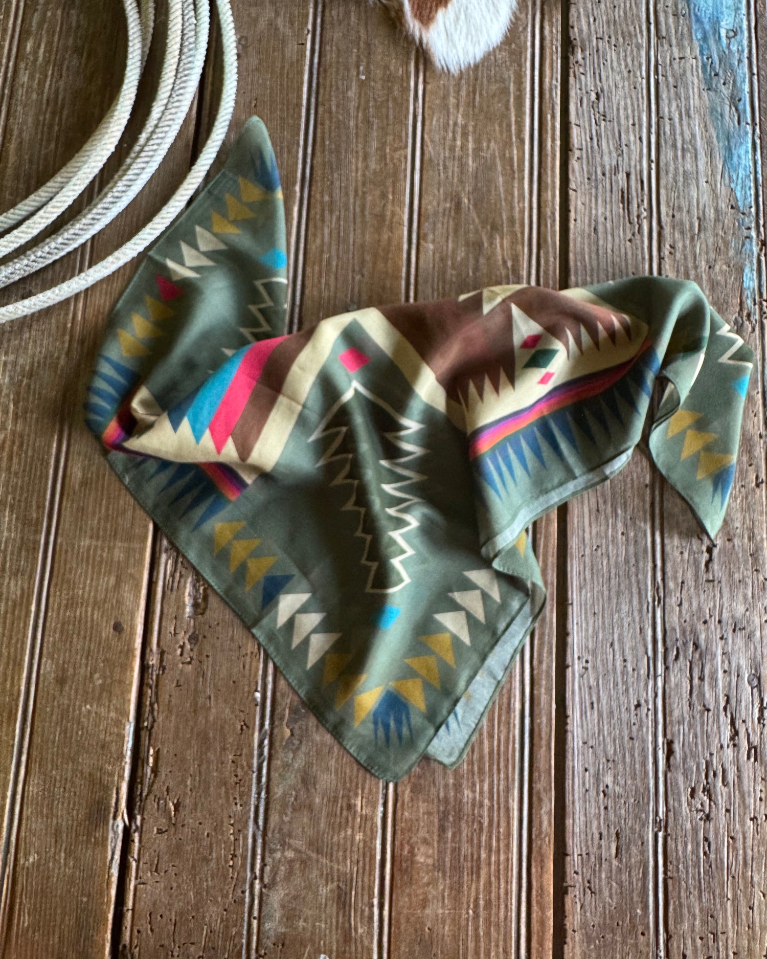 Colorful patterned bandana on a wooden surface with a cowhide rug in the background