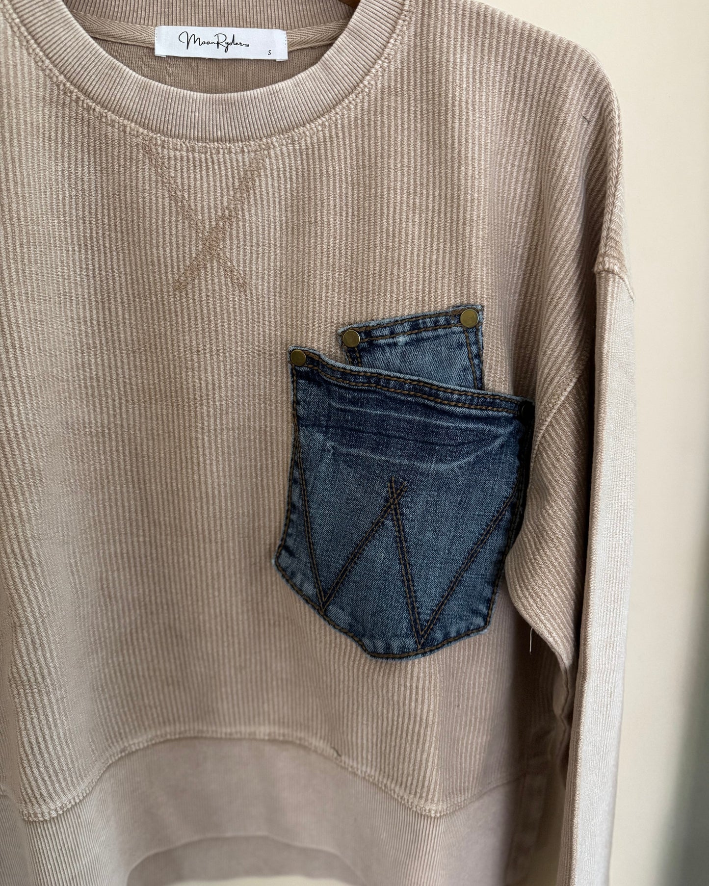 Beige sweatshirt with a blue denim pocket design on a white background