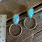 Turquoise stone earrings on a wooden surface with a ruler for scale.