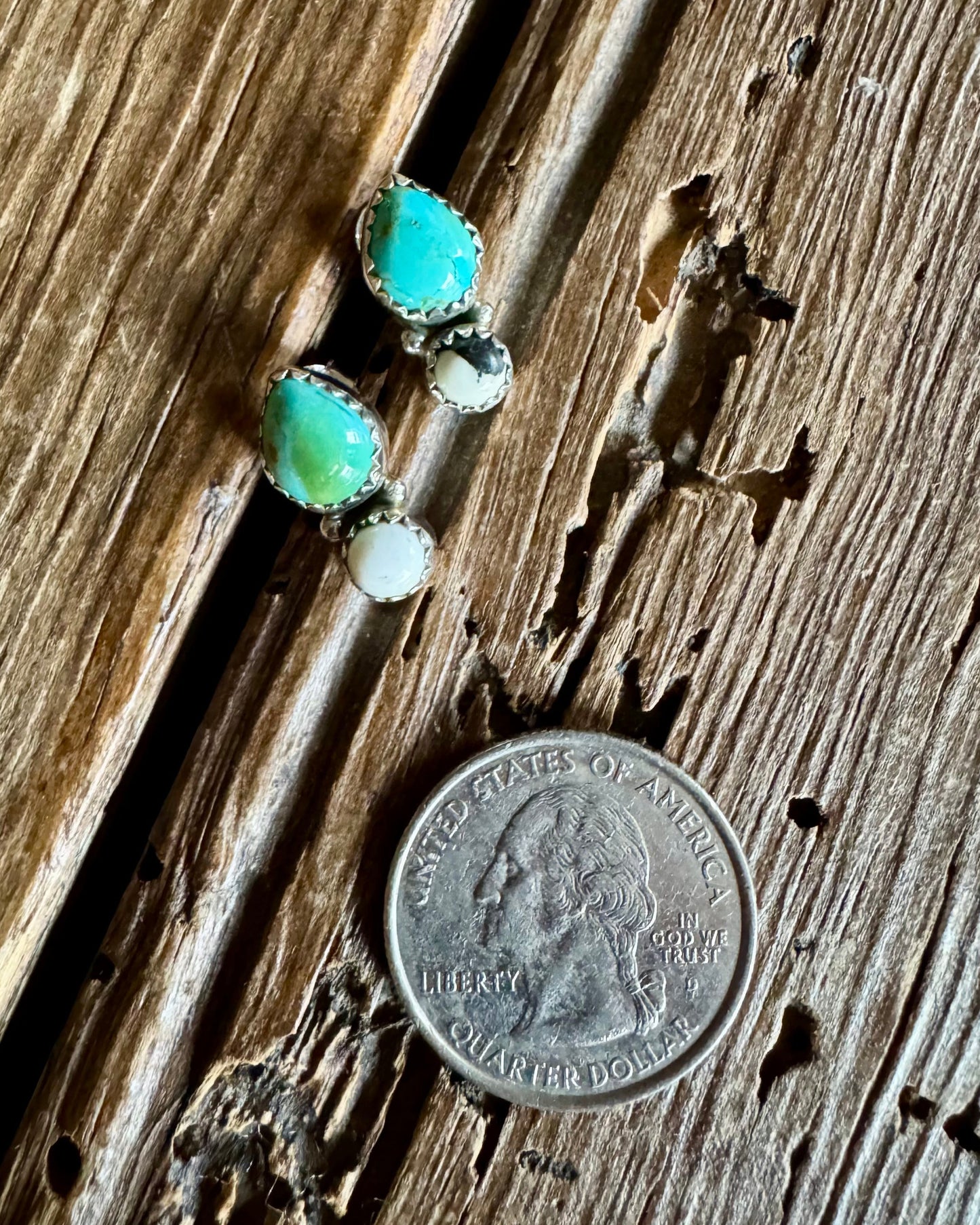 turquoise and white buffalo stud earrings on a rustic wood background with a quarter
