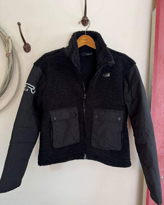 Black jacket with a brand logo hanging on a hook against a white wall.