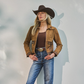 Woman wearing a brown jacket, jeans, and a cowboy hat against a light gray background