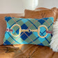 Decorative pillow with plaid pattern and equestrian design on a brown leather couch.