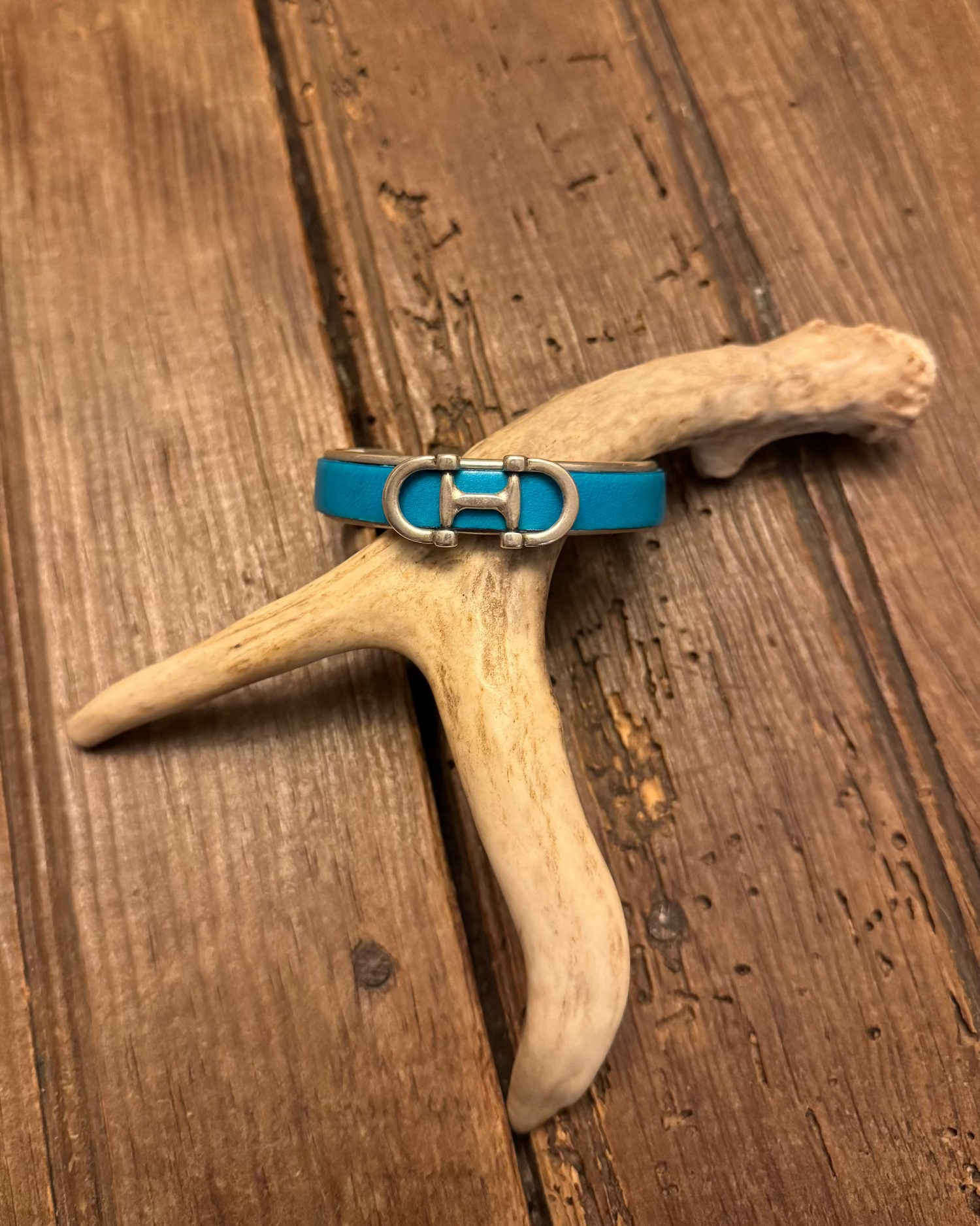 Blue cuff on a piece of driftwood on a wooden surface