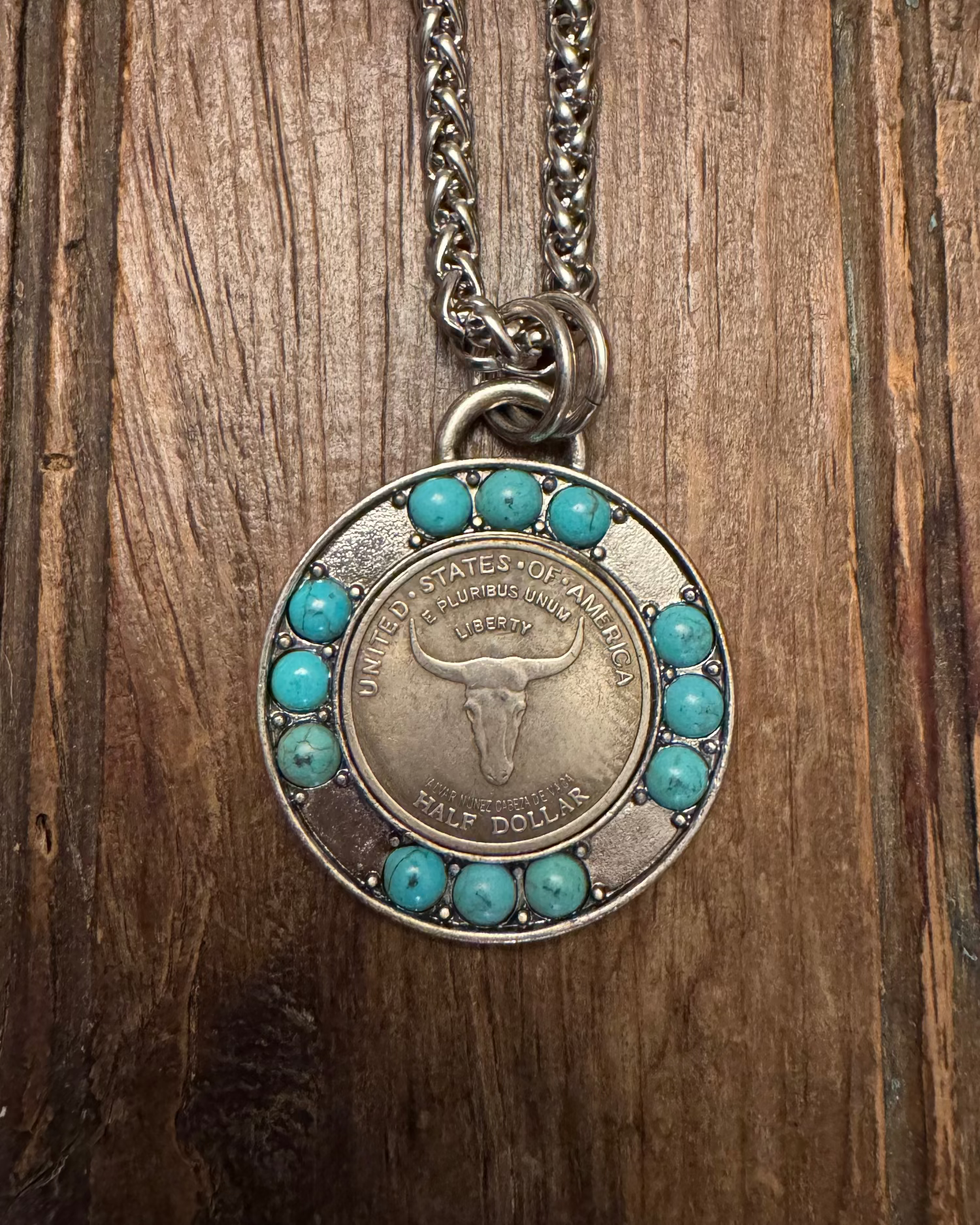 Necklace with a pendant featuring a coin design on a wooden surface