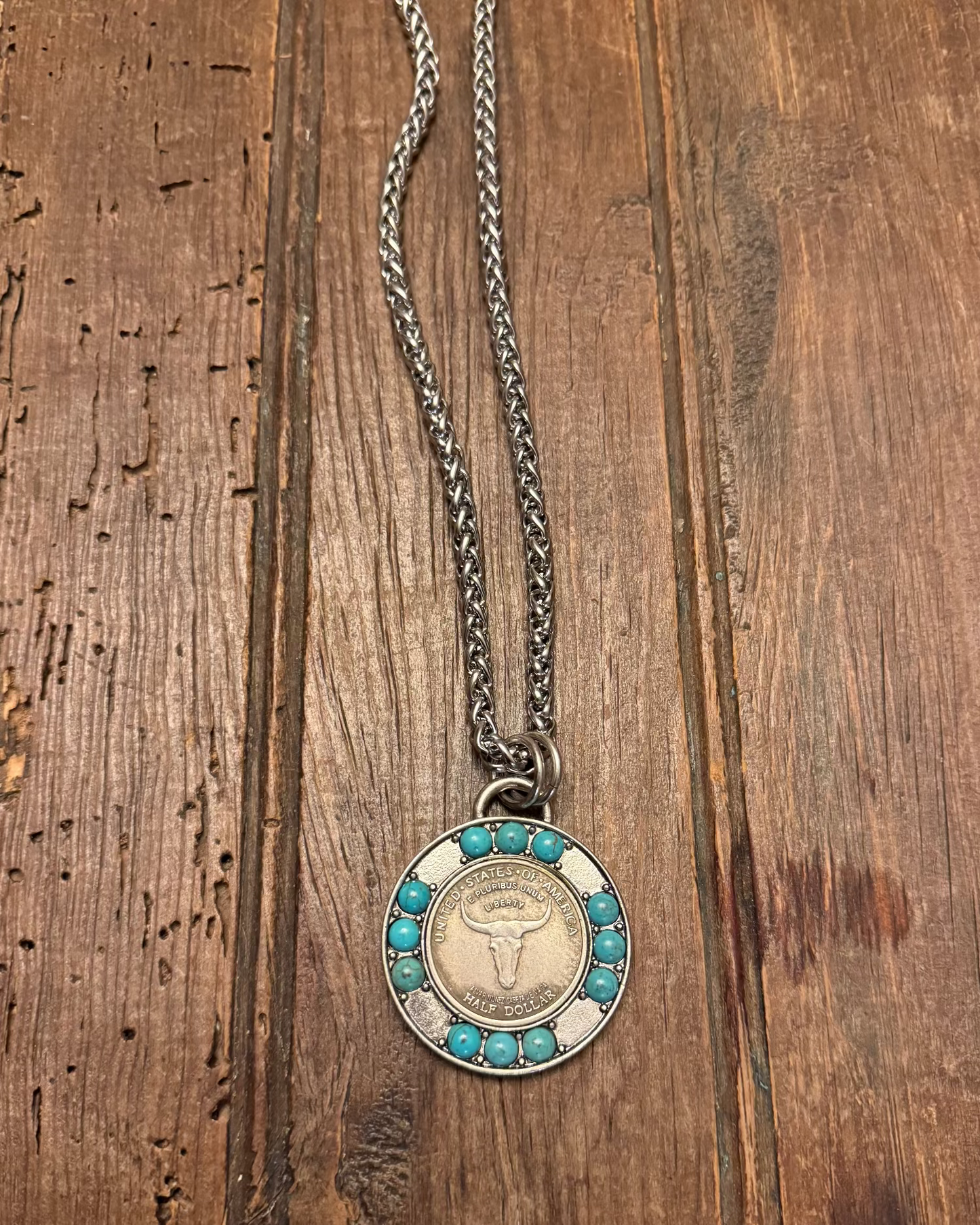 Necklace with a round pendant featuring a bull design on a wooden surface