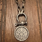 Silver padlock-shaped pendant on a chain against a wooden background