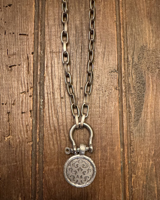 Silver necklace with a pendant on a wooden surface