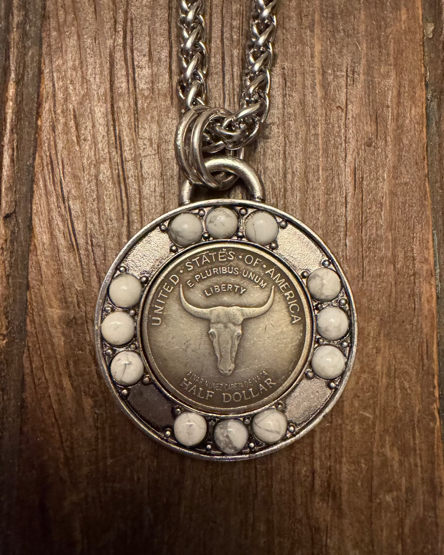 Silver necklace with a round pendant featuring a bull's head design on a wooden background