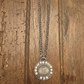 Silver necklace with a round pendant on a wooden surface