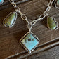 A silver-toned chain necklace with multiple turquoise stone pendants, including a large diamond-shaped pendant in the center and two smaller teardrop pendants on either side, displayed on a rustic dark wood surface.