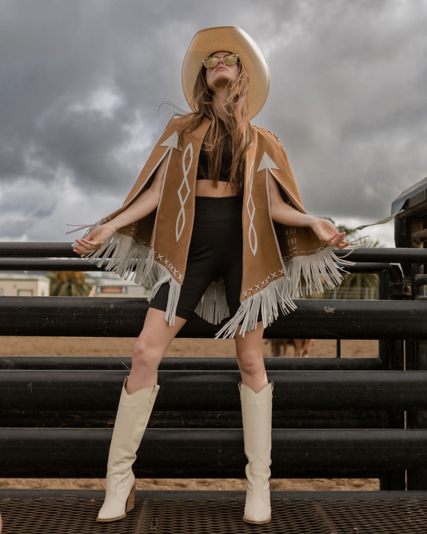 Woman wearing brown leather cape standing by a bucking chute