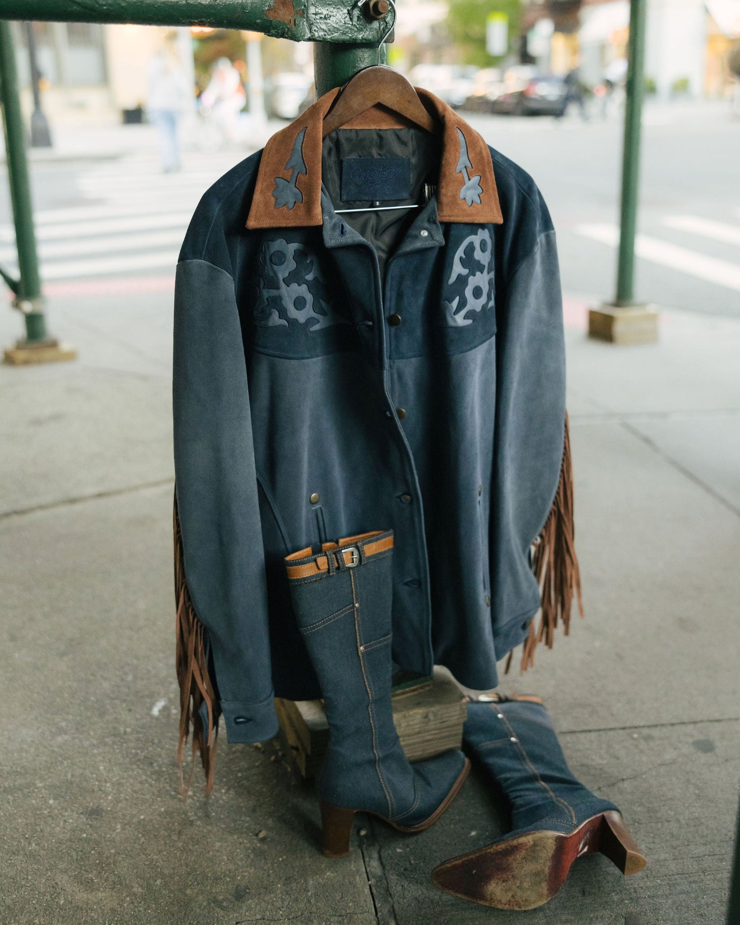 Blue denim jacket with brown leather accents on a mannequin outdoors.